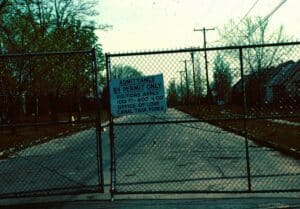 Image of a fence with a sign that says "Admittance by Permit Only. Visitors Apply 1001 97'' 800' 400'' Office of Love Canal Task Force"