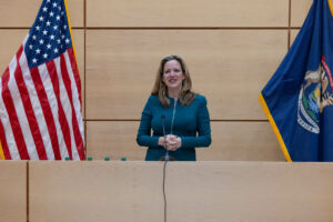 Jocelyn Benson opening remarks in front of flag March 2024